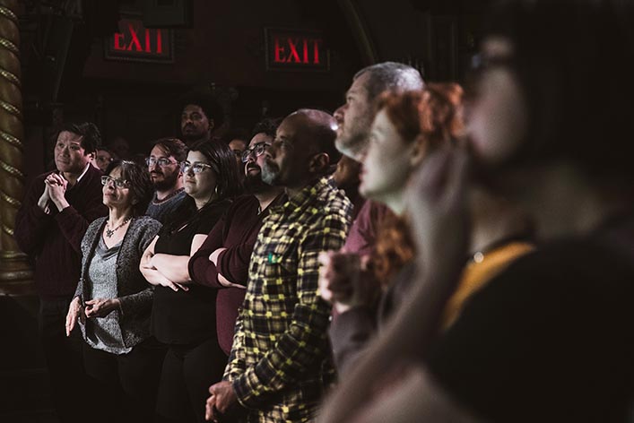 People listen to speeches after the closing performance of a play.