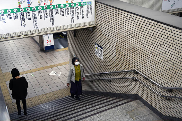 Woman climbs steps in a Tokyo metro station.