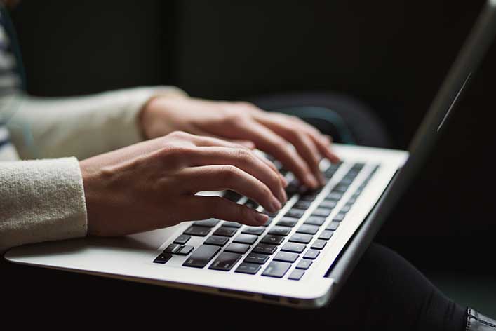 A woman writes on a laptop. Content development is the process of creating content to achieve a strategic goal.