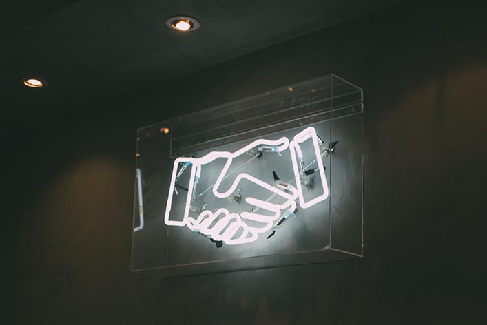 A neon sign depicting a handshake. 