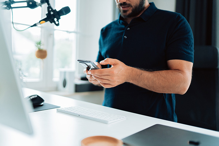 Man working at a laptop with a mobile phone in his hand (Malte Helmhold/Unsplash)