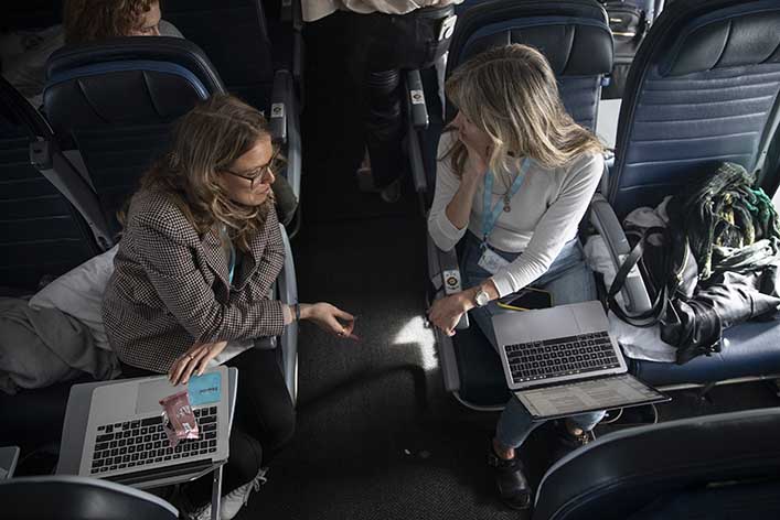 Women have a discussion on an airplane. Sharing new marketing trends, like thought leadership content, helps brands evolve.