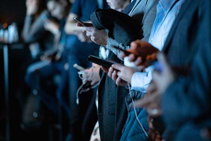 People in suits check their mobile phones. Content marketing is one of the most effective strategies for engaging audiences.